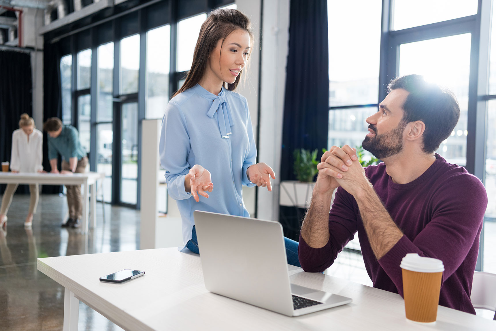 co-workers talking near a laptop