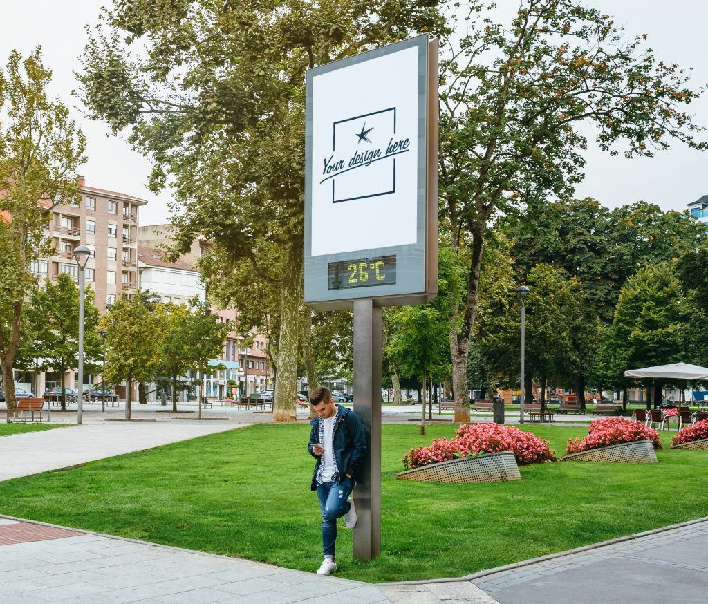 Man looking mobile leaning on a customizable billboard Man looking at mobile phone image